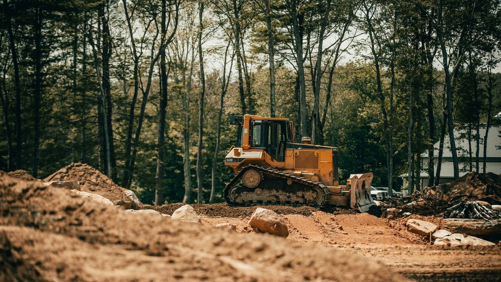 Bulldozer clearing and grading land near trees